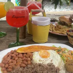 Bebidas y comida en una mesa de madera. Hay dos copas con bebidas, una hamburguesa con papas fritas, y un plato con arroz, frijoles, huevo frito y plátano. Es hora de pedir la cuenta en inglés.