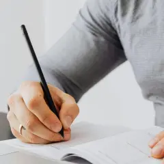 Persona escribiendo en un cuaderno, aprendiendo como empezar carta en ingles.