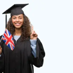 Graduada con toga y birrete, sostiene la bandera del Reino Unido y levanta un dedo, lista para su b1 ingles first.