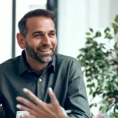 Hombre sonriente con barba, compartiendo ideas y mostrando emociones en inglés durante una conversación.