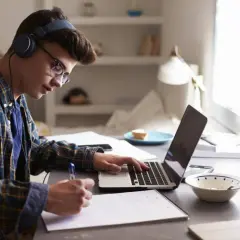 Joven concentrado estudiando con auriculares y portátil, preparándose para como sacarse el first por libre.