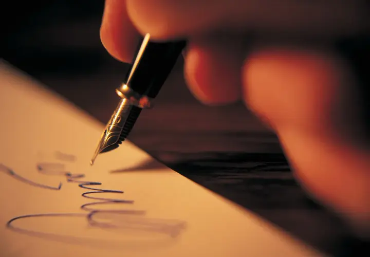 Mano escribiendo una carta informal con pluma fuente.