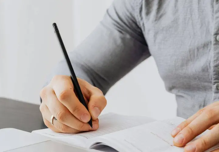 Persona escribiendo en un cuaderno, aprendiendo como empezar carta en ingles.