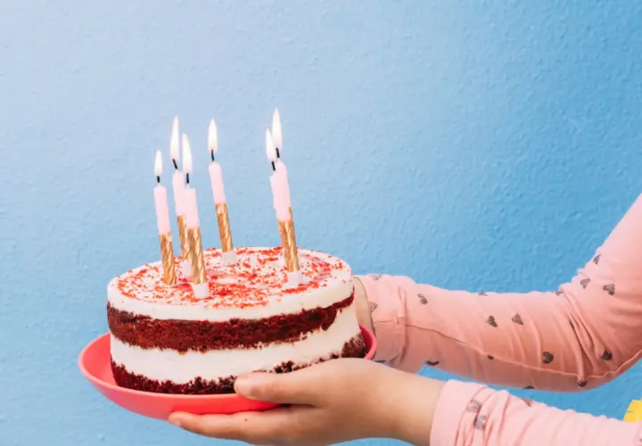Pastel de cumpleaños con velas encendidas, listo para decir "feliz cumpleaños en ingles".