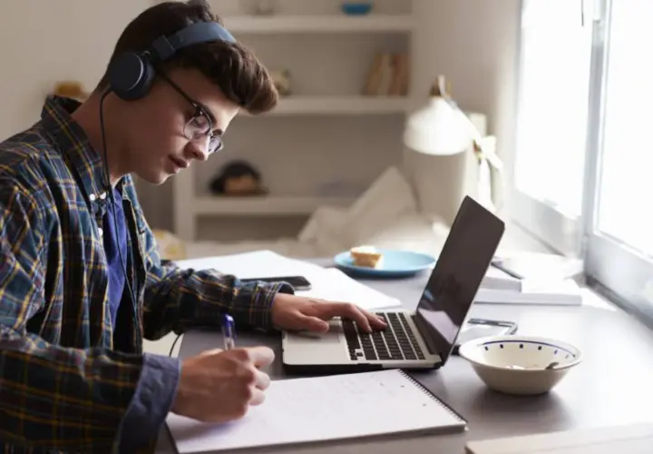 Joven concentrado estudiando con auriculares y portátil, preparándose para como sacarse el first por libre.
