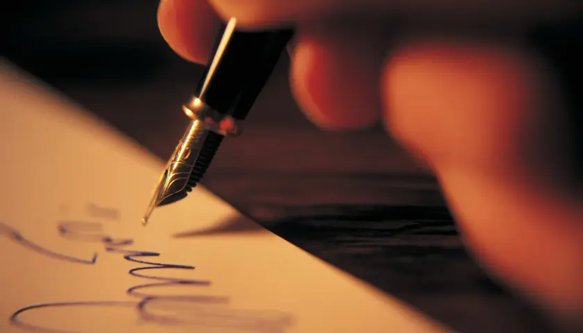 Mano escribiendo una carta informal con pluma fuente.