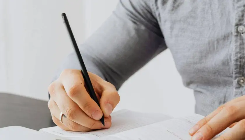 Persona escribiendo en un cuaderno, aprendiendo como empezar carta en ingles.