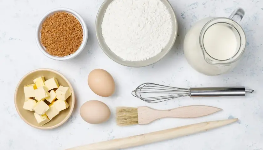 Ingredientes para hornear: harina, azúcar, mantequilla, huevos, leche, batidor, brocha y rodillo.