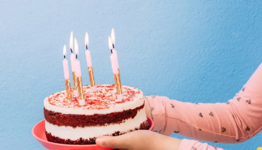 Pastel de cumpleaños con velas encendidas, listo para decir "feliz cumpleaños en ingles".