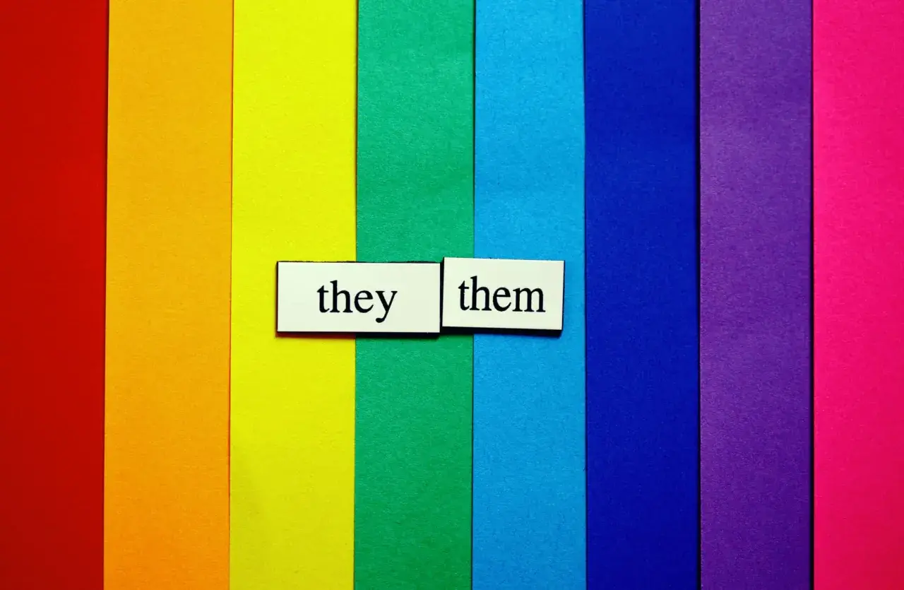 Fondo arcoíris con tarjetas que dicen "they" y "them", representando pronombres personales en inglés.
