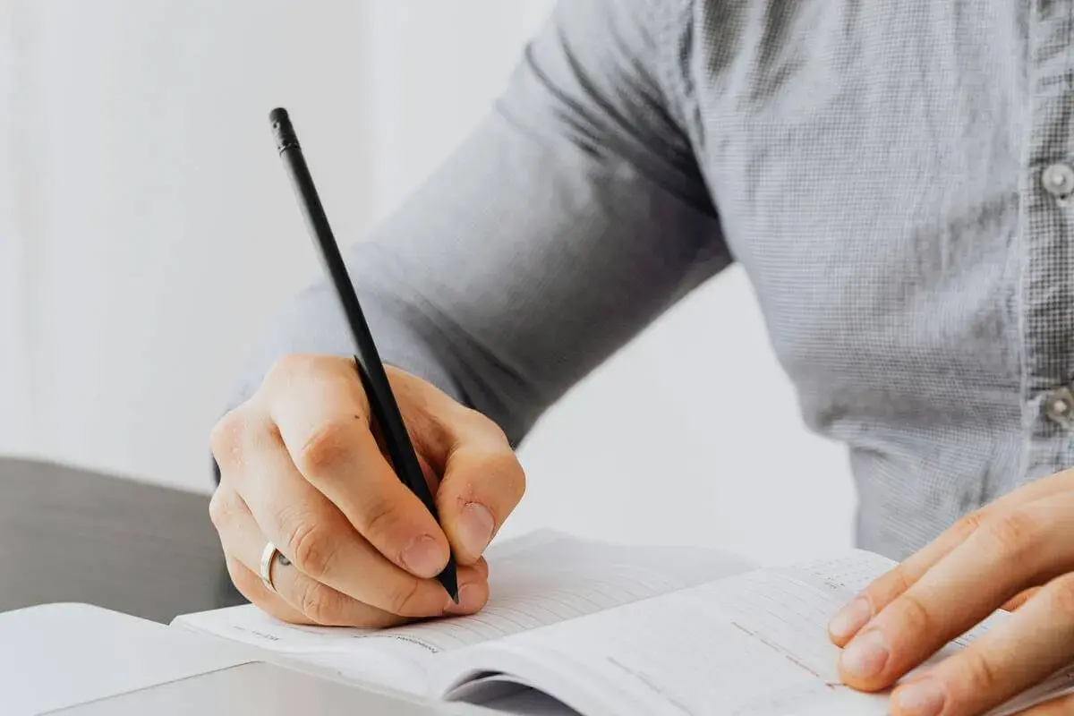 Persona escribiendo en un cuaderno, aprendiendo como empezar carta en ingles.
