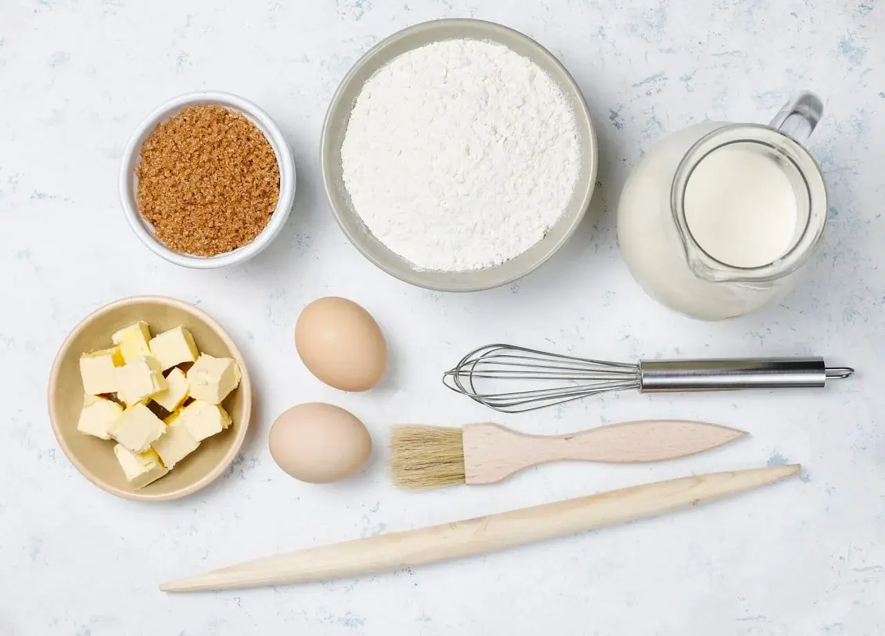 Ingredientes para hornear: harina, azúcar, mantequilla, huevos, leche, batidor, brocha y rodillo.