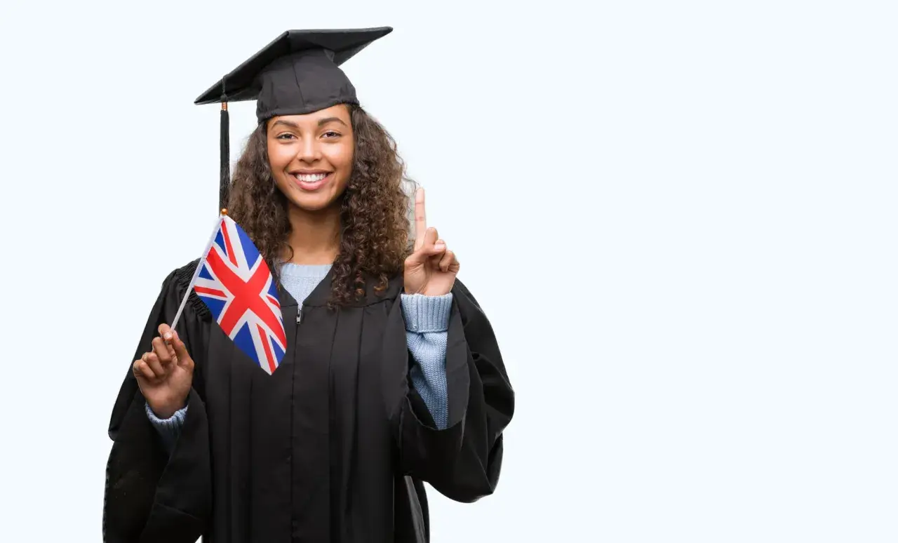 Graduada con toga y birrete, sostiene la bandera del Reino Unido y levanta un dedo, lista para su b1 ingles first.
