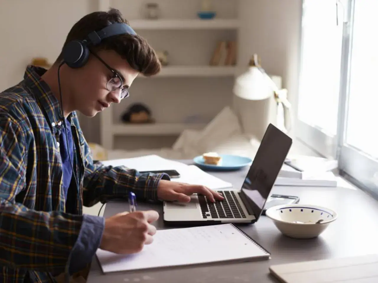Joven concentrado estudiando con auriculares y portátil, preparándose para como sacarse el first por libre.